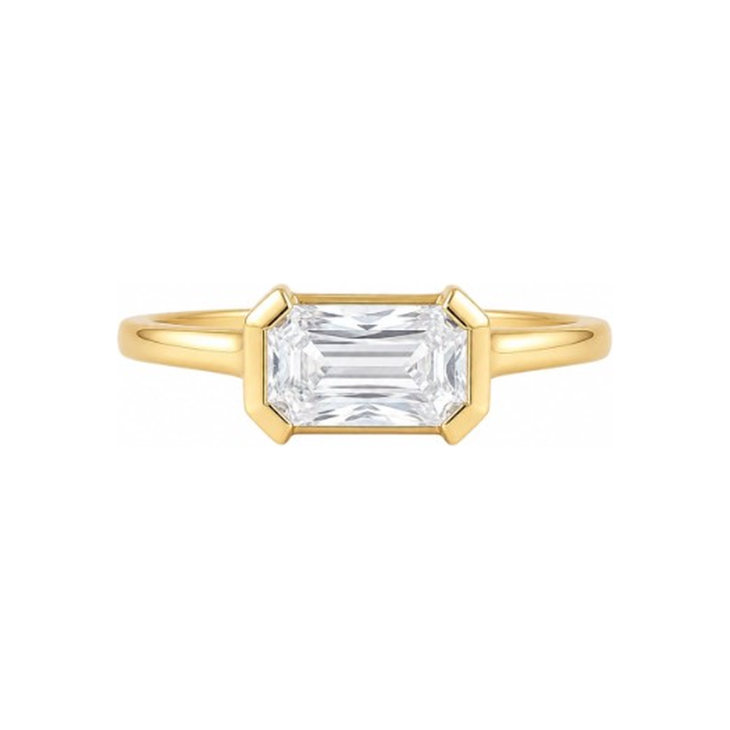 A yellow gold ring featuring a large rectangular emerald-cut clear gemstone in a prong setting, shown against a plain white background.