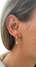 A close-up of a person's ear wearing a Gold on Sterling Silver Round Cubic Zirconia Drop Earrings.
