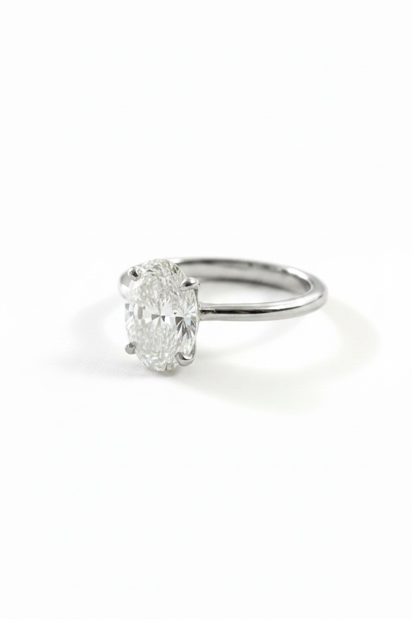 An oval-cut diamond engagement ring in a silver-toned four-prong setting on a plain white background.