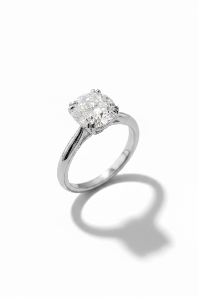 A classic solitaire engagement ring featuring a round brilliant-cut diamond set in a polished silver-colored metal band, photographed on a clean white background with a soft shadow.